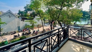 A balcony with a metal railing overlooking a street with parked scooters and a building with traditional architecture. - Hoan Kiem Lake View / Balcony / 3Q Beds / 6 Pax (Hà Nội)