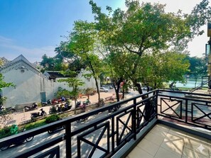 A balcony with a metal railing overlooking a street with parked scooters and a building with traditional architecture. - Hoan Kiem Lake View / Balcony / 3Q Beds / 6 Pax (Hà Nội)
