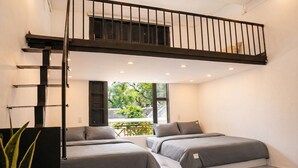 Un dormitorio moderno con dos camas, una zona de descanso elevada y vistas a zonas verdes.