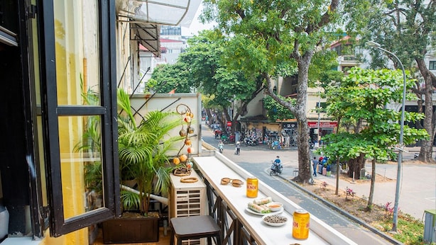A balcony with a table, chairs, and a view of the street. - Hoan Kiem Lake View / Balcony / 3Q Beds / 6 Pax (Hà Nội)