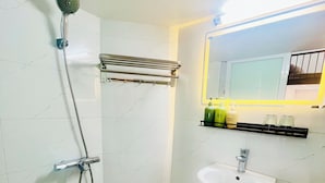 A bathroom with a shower, a sink, a towel rack, and a mirror with a light. - Hoan Kiem Lake View / Balcony / 3Q Beds / 6 Pax (Hà Nội)