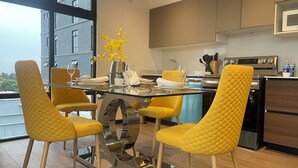 Un comedor moderno con una mesa de vidrio, sillas amarillas y un jarrón con flores amarillas.