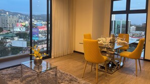 Un comedor moderno con una mesa de vidrio, sillas amarillas y vistas a la ciudad a través de amplios ventanales.
