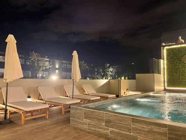 A rooftop pool area with lounge chairs and umbrellas, a small pool, and a green wall feature. - Luxurious Apt. Z.10 GT City | 2Bedroom | AC | Wifi | Parking | Swimming Pool Jacuzzi (Ciudad de Guatemala)