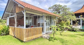 Ein Haus mit Wintergarten, einer Holzterrasse und einem Garten mit Pflanzen und Pool.