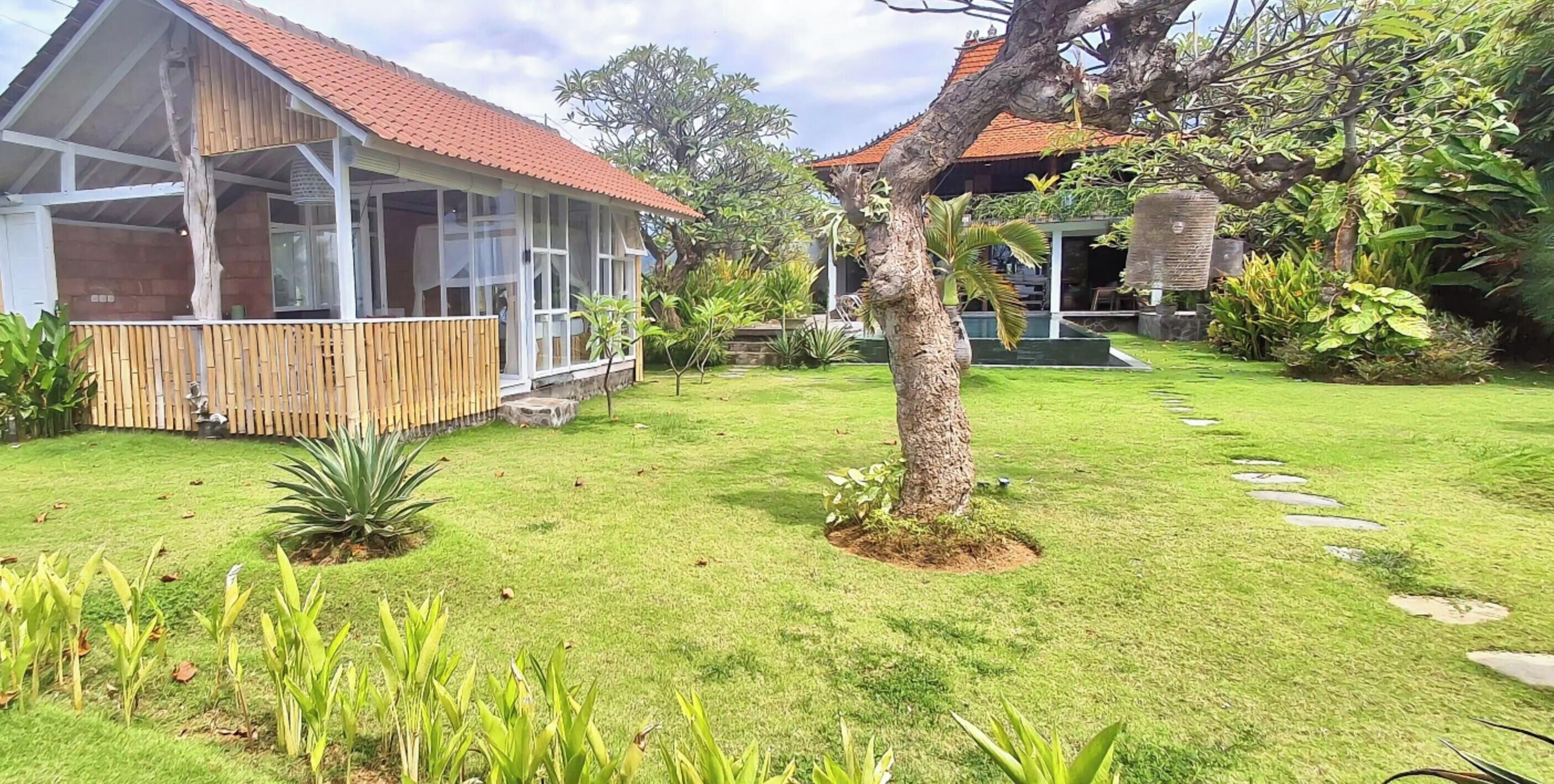 A house with a covered porch, a garden with a lawn and stepping stones, and a tree.