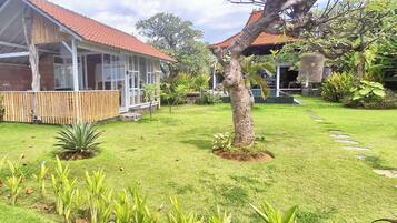 A house with a covered porch, a garden with a lawn and stepping stones, and a tree.