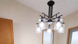 A dining area with a long table, black chairs, a wooden cabinet, and a modern chandelier.