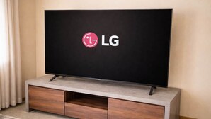 A flat-screen TV on a wooden TV stand with a logo on the screen.