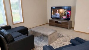A living room with a flat-screen TV, two sofas, a coffee table, and a rug.