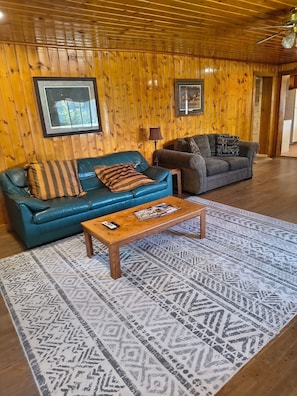 A wooden-paneled room with two sofas, a patterned rug, and framed pictures on the wall. - Walden Legacy Lodge – North Park Basecamp - Hunt, Fish, Hike, and Snowmobile (Walden)