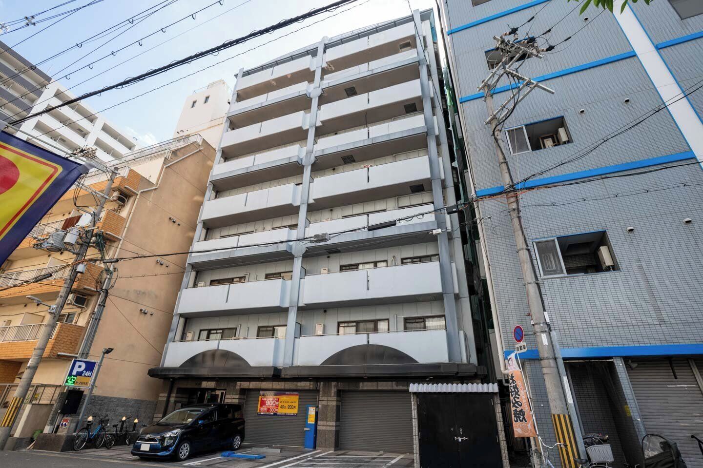 A multi-story building with a parking garage entrance, a bicycle rack, and a sign indicating a parking area.