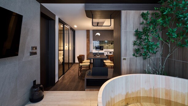 Un interno moderno con zona pranzo, cucina e una grande vasca da bagno in legno.