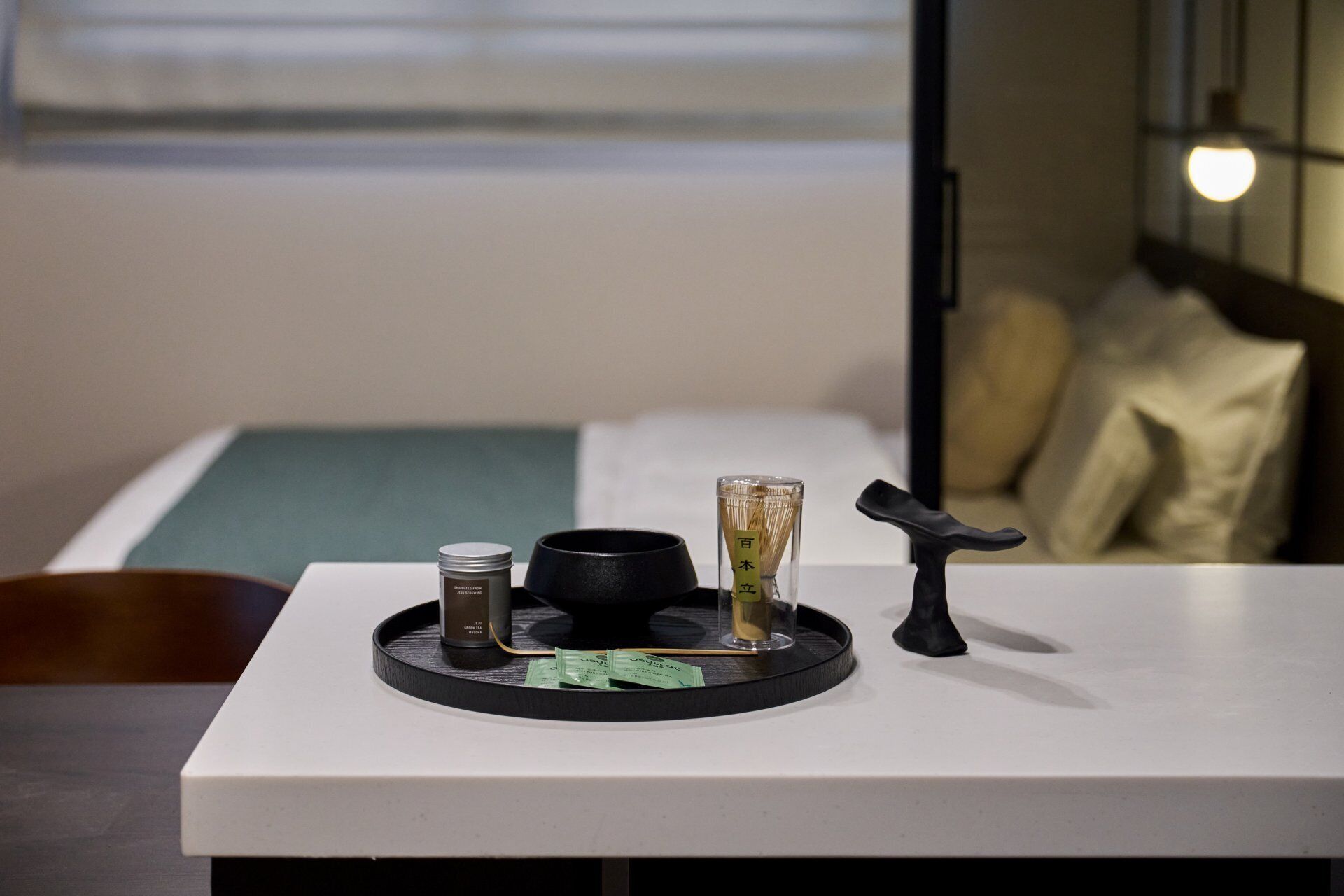 A minimalist table with a tea set, a candle, and a decorative item.