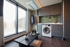 A modern kitchen with a built-in washer, a large window, and a dark wooden table with a vase. - Loop Seoul Hotel by Anook Seoul Gangnam 2 (Seoul)