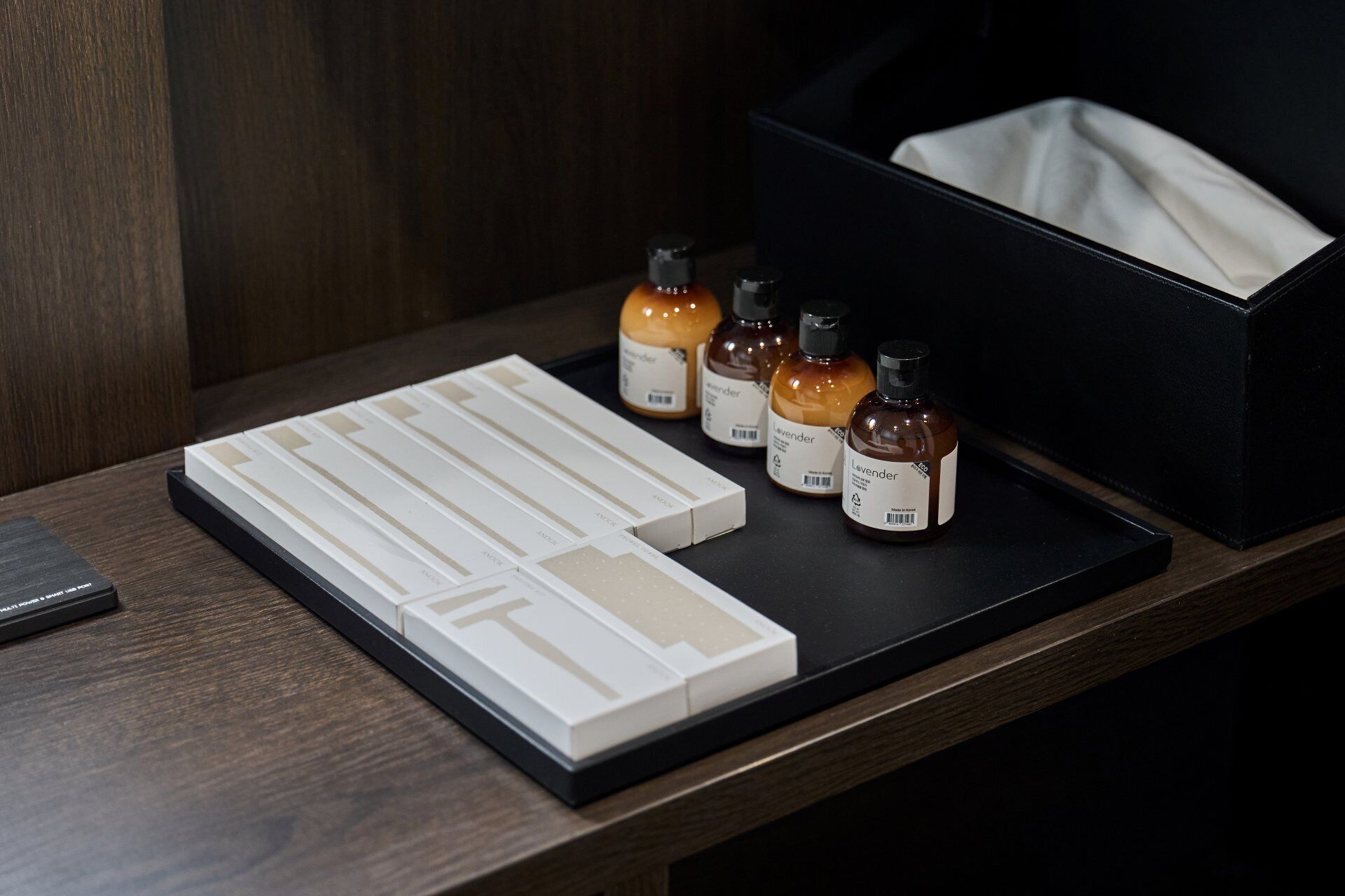 A wooden table with a black tray holding several small bottles labeled 'Lavender' and a white box with compartments.
