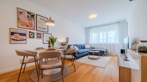 Uma sala de estar moderna com área de jantar, sofá e televisão.