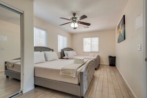 Ein Schlafzimmer mit einem Bett, einem Deckenventilator und einem Fenster mit Jalousien.