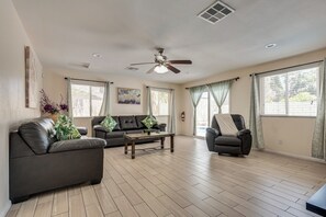 Ein geräumiges Wohnzimmer mit Deckenventilator, einer Couch, einem Sessel und einem Couchtisch.