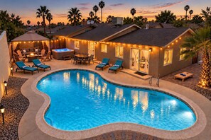 Piscina com espreguiçadeiras e hidromassagem, cercada por um terraço com luzes de Natal.