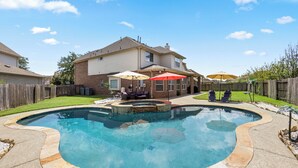 Un jardin avec une piscine, un espace barbecue et une clôture en bois.