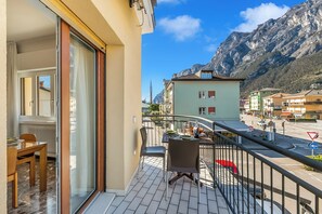 Ein Balkon mit Tisch und Stühlen, Blick auf einen Berg und Gebäude im Hintergrund.