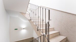 Un escalier avec des rampes et une main courante en métal, menant à un palier où se trouve un luminaire.