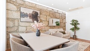 Un coin repas avec un mur en pierre, un tableau, un vase de fleurs, un canapé et une plante en pot.