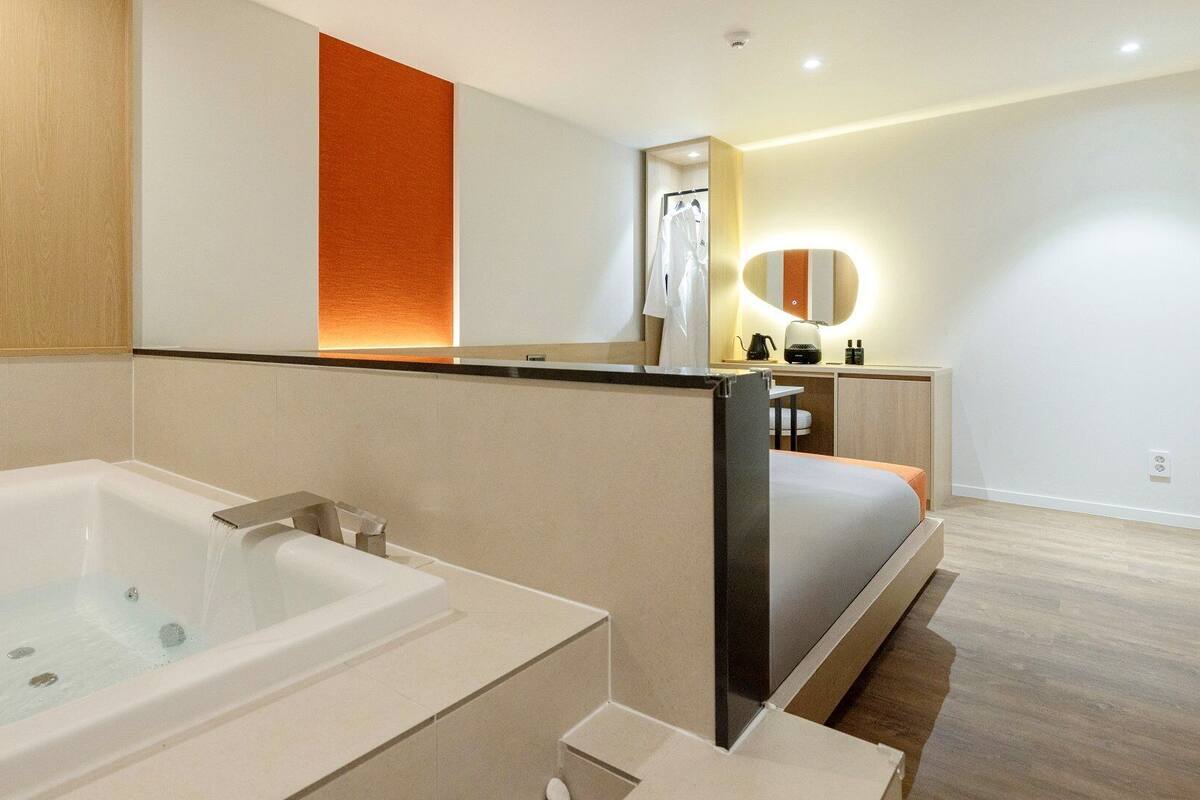 Un baño moderno con bañera, zona de ducha y tocador con espejo.