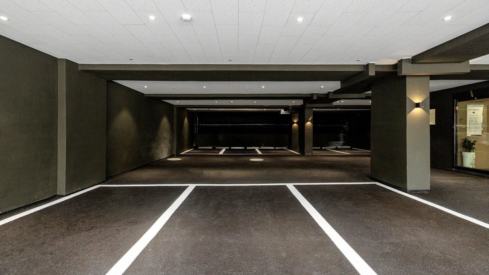 Un garaje para estacionar con varios niveles, pilares de concreto y una zona de recepción.