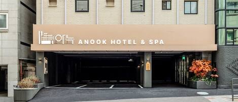 The exterior of Anook Hotel & Spa with a modern facade, a covered entrance, and potted plants.