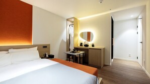 Ett hotellrum med en säng, ett skrivbord, en spegel och en garderob.