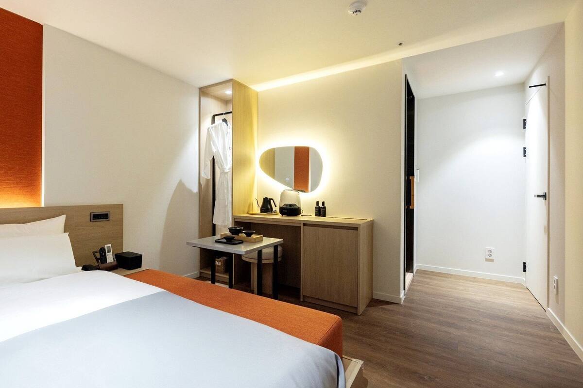 Una habitación de hotel con cama, escritorio, espejo y armario.