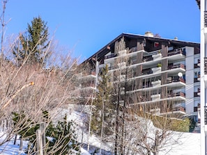 A multi-story building with balconies, surrounded by trees and snow. - Clair-Azur B 35 by Interhome (Crans-Montana)