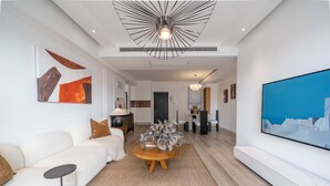 Un salon moderne avec un canapé blanc, une table basse ronde et un grand téléviseur à écran plat.