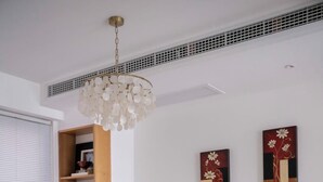 Un coin repas avec une table ronde, des chaises noires, un vase et des œuvres d’art accrochées au mur.