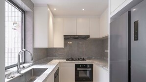 Une cuisine compacte dotée d’un four encastré, d’un évier en acier inoxydable et d’une cuisinière moderne.