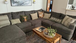 Uma sala de estar moderna com um sofá seccional, uma mesa de centro de madeira e um tapete estampado.