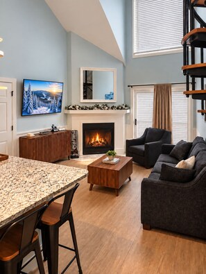 Una sala de estar moderna con chimenea, televisor y comedor.