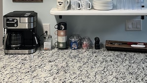 A kitchen with shelves holding pots, plates, mugs, and a coffee maker. - Whistlepunk #43: 1 Bedroom With Loft, Slopeside (Snowshoe)