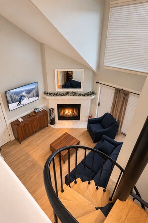 Ein modernes Wohnzimmer mit Kamin, Fernseher und einer Treppe.