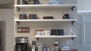 A kitchen with granite countertops, a coffee maker, bar stools, and shelves with kitchenware. - Whistlepunk #43: 1 Bedroom With Loft, Slopeside (Snowshoe)