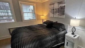 A bedroom with a bed, a nightstand, a lamp, a ceiling fan, and a window. - Whistlepunk #43: 1 Bedroom With Loft, Slopeside (Snowshoe)