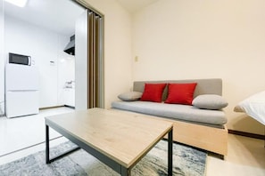 A modern room with a sofa, a small table, and a bed.