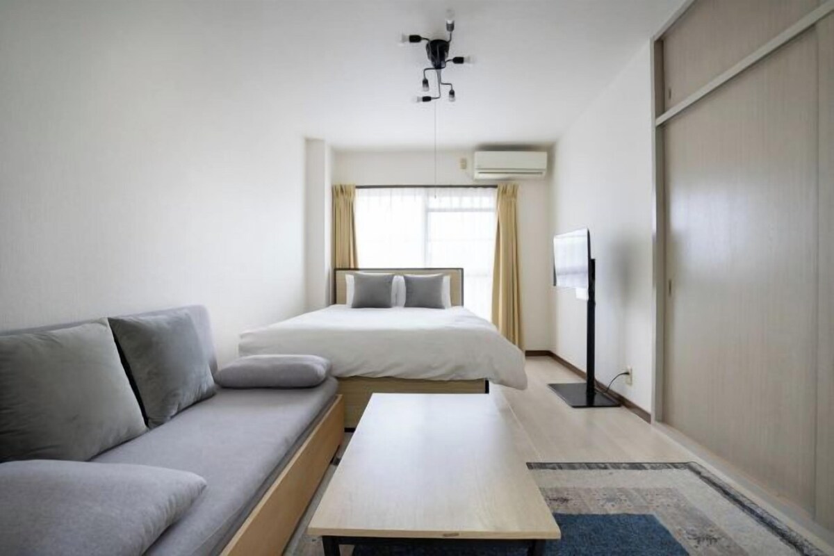 A modern hotel room with a bed, sofa, and a flat-screen TV.