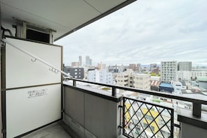 A balcony with a city view, a white cabinet, and a metal railing.