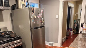 Una cocina con refrigerador de acero inoxidable, estufa y piso de madera.