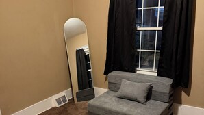 Un dormitorio con cama, un espejo grande y una ventana con cortinas negras.
