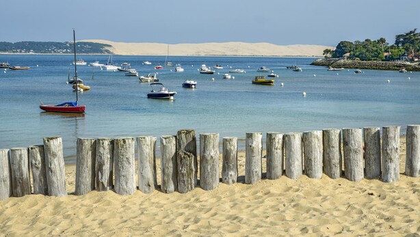A beach with wooden posts, boats, and a sandy shore. - Superbe maison avec piscine (Andernos-les-Bains)