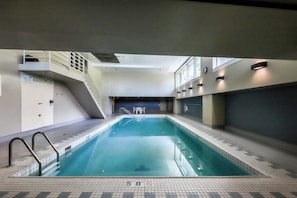 An indoor swimming pool with a 50 ft depth marker, a staircase, and a seating area. - Newmark condo near attractions with heated pool, hot tub, & fitness room (Seattle)